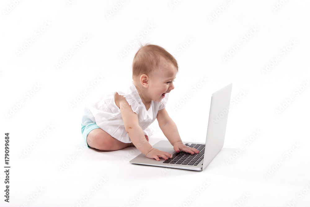 curious smiling child sitting near the laptop on a white background curious smiling child sitting near the laptop on a white background