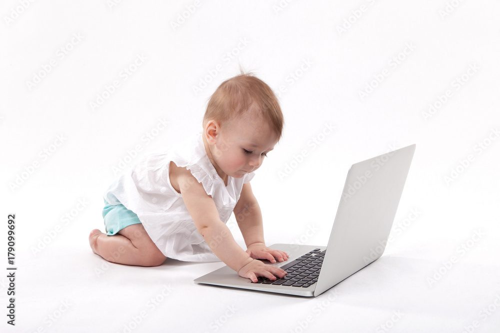 curious smiling child sitting near the laptop on a white background curious smiling child sitting near the laptop on a white background