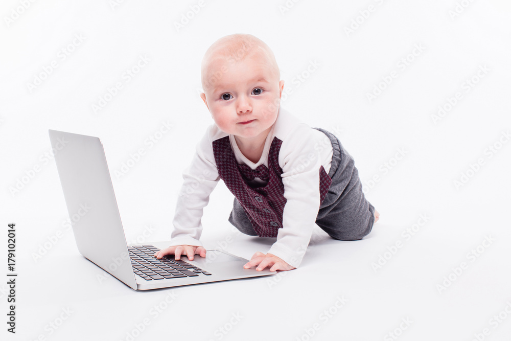cute little baby boy sitting on a white background in front of a laptop and learns to type on it cute little baby boy sitting on a white background in front of a laptop and learns to type on it