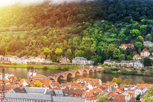 Europe culture concept - panoramic city skyline birds eye aerial view under dramatic sun and morning blue cloudy sky in Heidelberg, Germany.