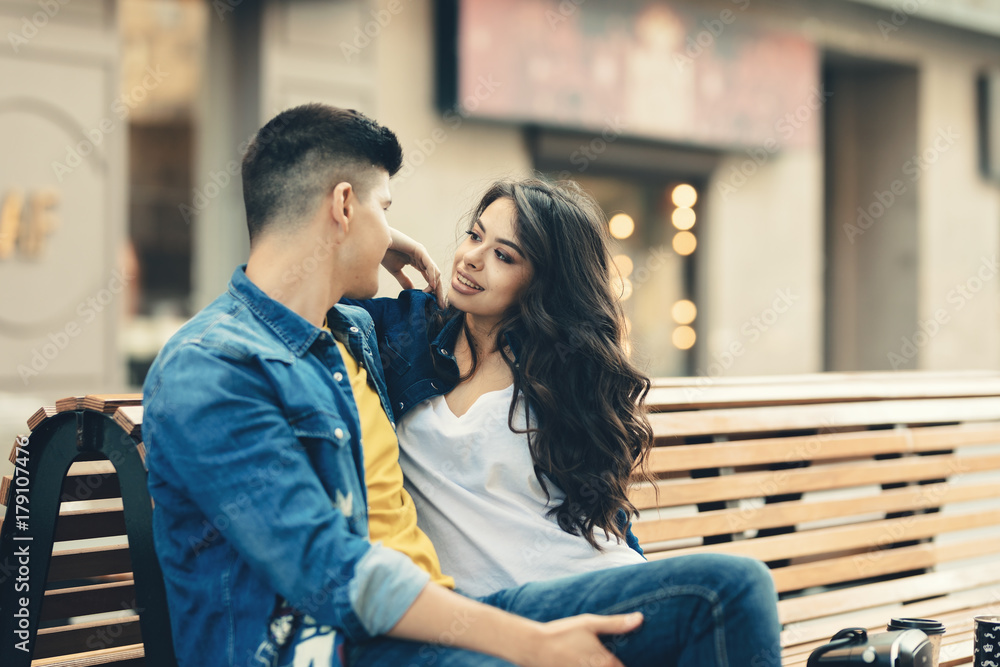 Romantic young couple having fun in the city spending time together. Smiling couple in love drinking coffee on the street.Excited happy couple full of affection and romance, hugging on the city street