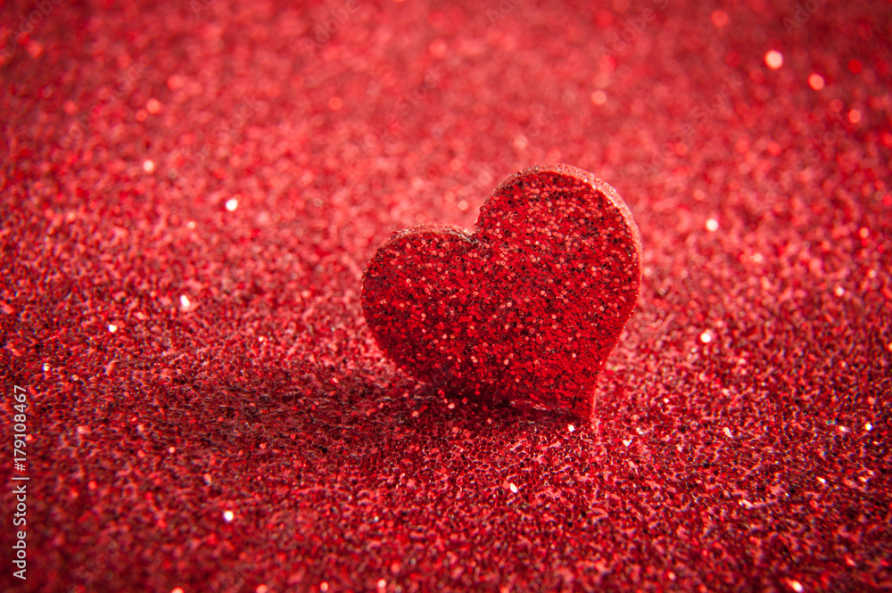 Fototapeta premium Valentines bright red heart on a red glitter background.
