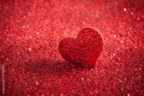 Valentines bright red heart on a red glitter background.