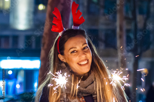 Close up of woman holding sparkler on the street. Young woman celebrating an event the New Year is coming