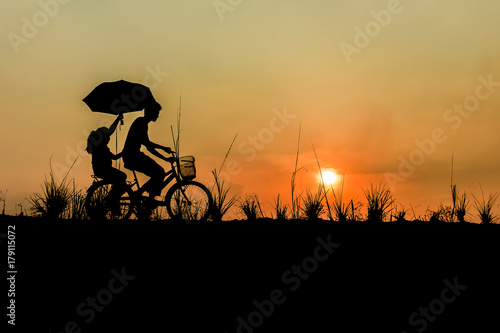 brother with sister riding bikes at sunset