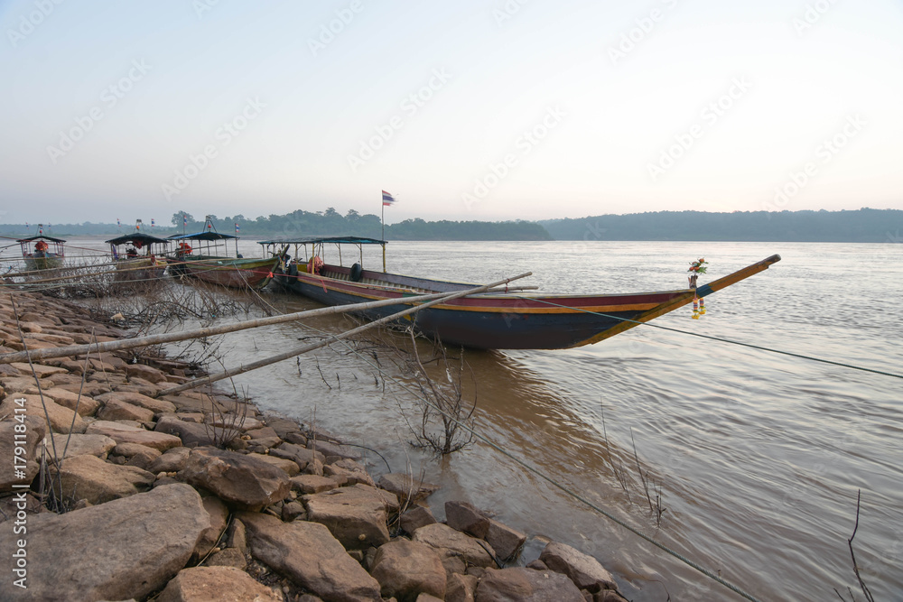 Passenger boat crossing the Thai-Laos border with the Thai flag on the Mekong River at dawn.
