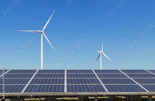    solar cells with wind turbines generating electricity in hybrid power plant systems station on blue sky background alternative renewable energy from nature  Ecology concept.   