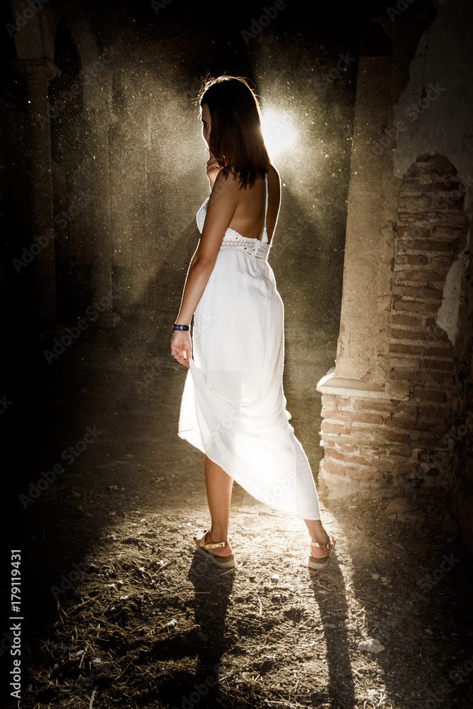 Mujer con vestido blanco a contraluz en el templo antiguo