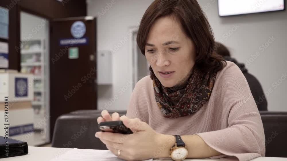 A happy woman is checking email on her smartphone while sitting at the table. A happy woman is checking email on her smartphone while sitting at the table.