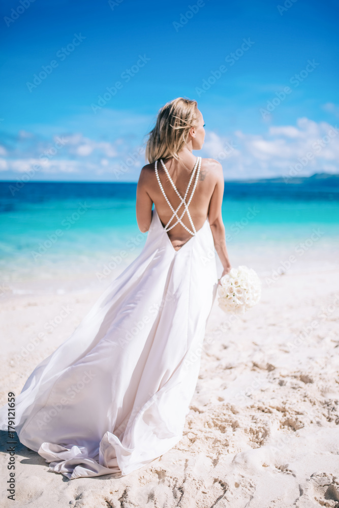 Beautiful bride in long white dress on the beach with white bouquet Beautiful bride in long white dress on the beach with white bouquet