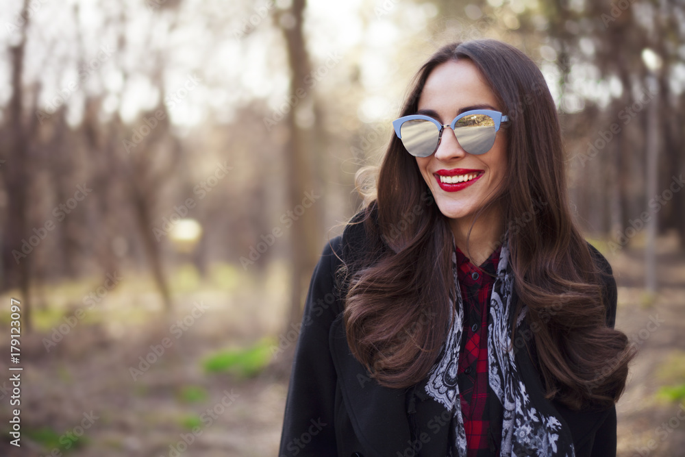 stylish brunette young woman with red lips in fashionable sunglasses posing outdoors in park stylish brunette young woman with red lips in fashionable sunglasses posing outdoors in park