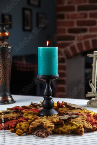 Fototapeta Naklejka Na Ścianę i Meble -  beautiful burning candle on the wooden carved candle holder stands holiday table