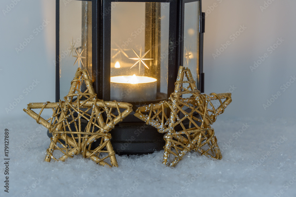 Laterne mit Kerze in der Laterne und goldener Sterne auf Schnee