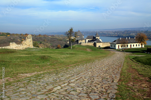 Ancient road paved with cobblestone and going to medieval fortress in Khotyn on hill above river.