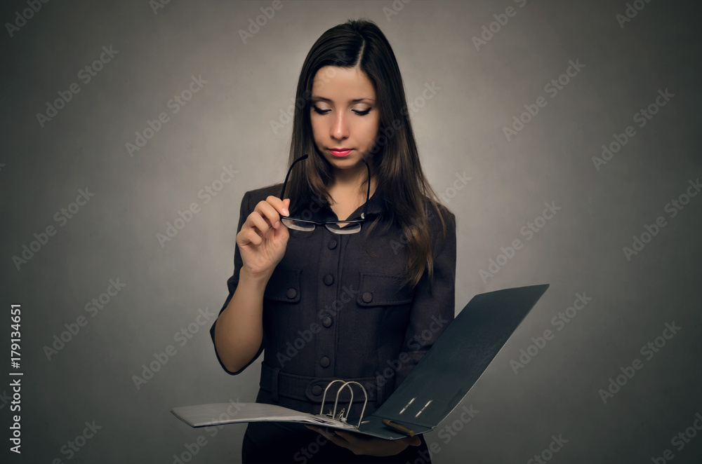 Young woman holding in hands document folder and searching some information within. Office paper work. Secretary woman. Young woman holding in hands document folder and searching some information within. Office paper work. Secretary woman.