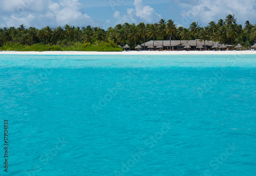 Tropical beach Maldives with palm trees and blue lagoon. Tropical island with coconut palm trees on white sandy beach. Maldives  Indian Ocean. Dreamlike beach luxury Islands. Untouched tropical beach.