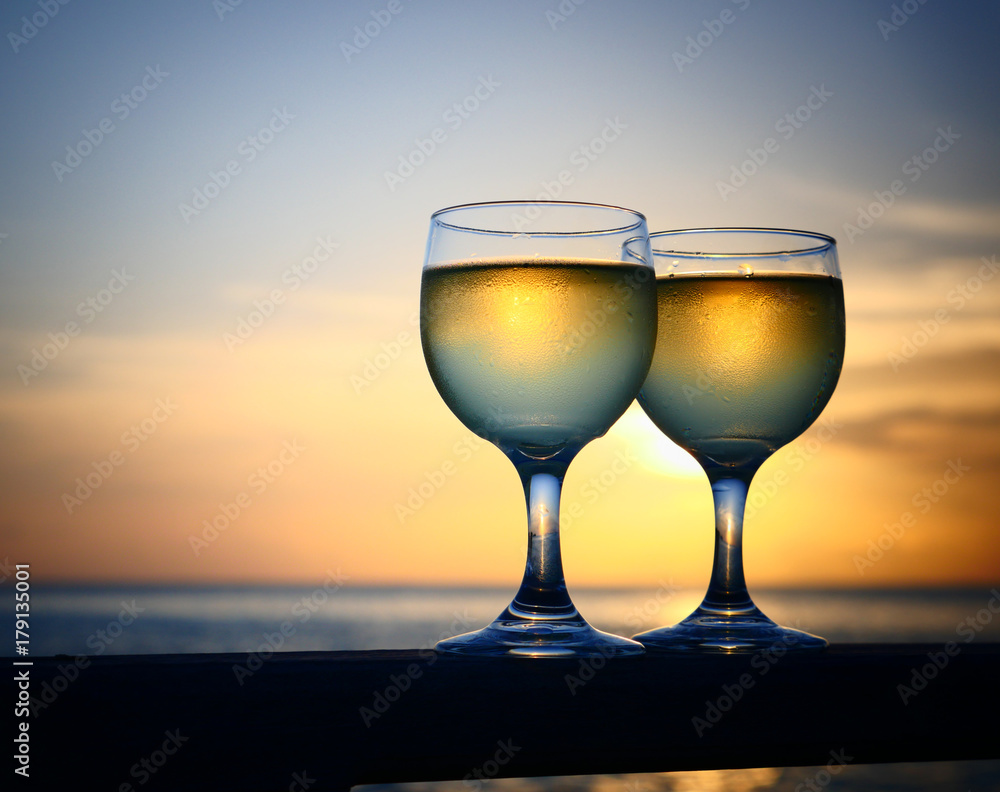 Romantic luxury evening on cruise yacht with winery setting. Glasses, white wine and tropical sunset with sea background. Vacation relax time on the sea with Two glasses of white wine. Maldives island