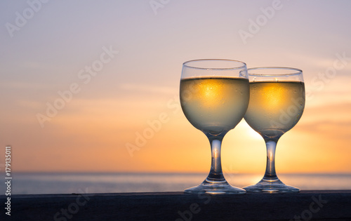 Romantic luxury evening on cruise yacht with winery setting. Glasses  white wine and tropical sunset with sea background. Vacation relax time on the sea with Two glasses of white wine. Maldives island