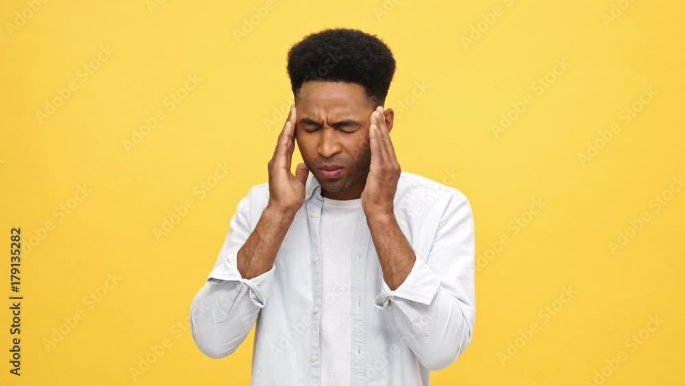 Young african man in shirt having headache and touching his temples over yellow background Young african man in shirt having headache and touching his temples over yellow background