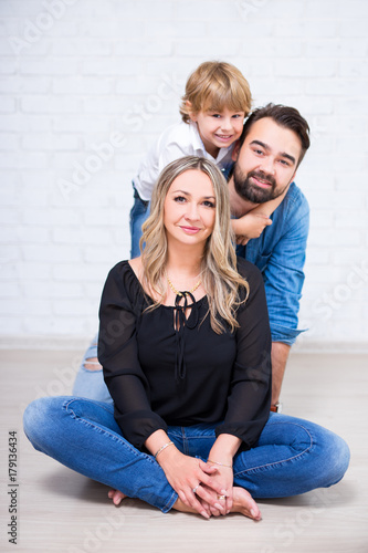 happy family portrait - young parents and little son posing over white brick wall