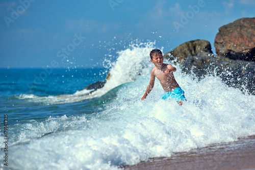 Cute Caucasian boy in sea waves.