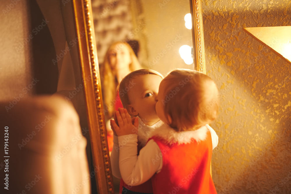 little girl kisses herself in the mirror - obrazy, fototapety, plakaty 