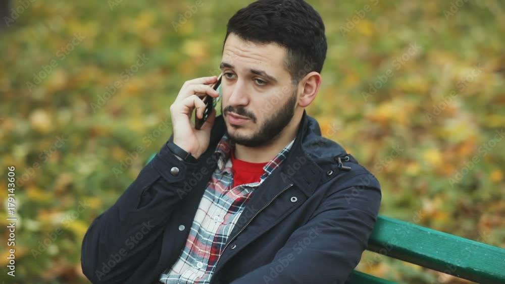 handsome young caucasian man outdoors talking smart phone mobile businessman student call conversation serious confident emotional face telephone speak bearded guy autumn sitting bench brunette urban handsome young caucasian man outdoors talking smart phone mobile businessman student call conversation serious confident emotional face telephone speak bearded guy autumn sitting bench brunette urban
