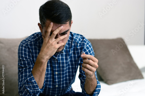 Divorce concept. Sad lonely man holding engagement ring sitting at home. Depression after a divorce. Selective focus.