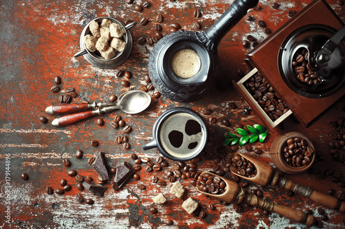 Black coffee in a cup on the table in a composition with coffee accessories on an old background