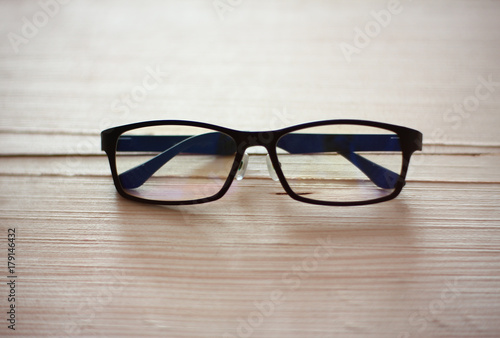  Black eyeglasses on wood plate.