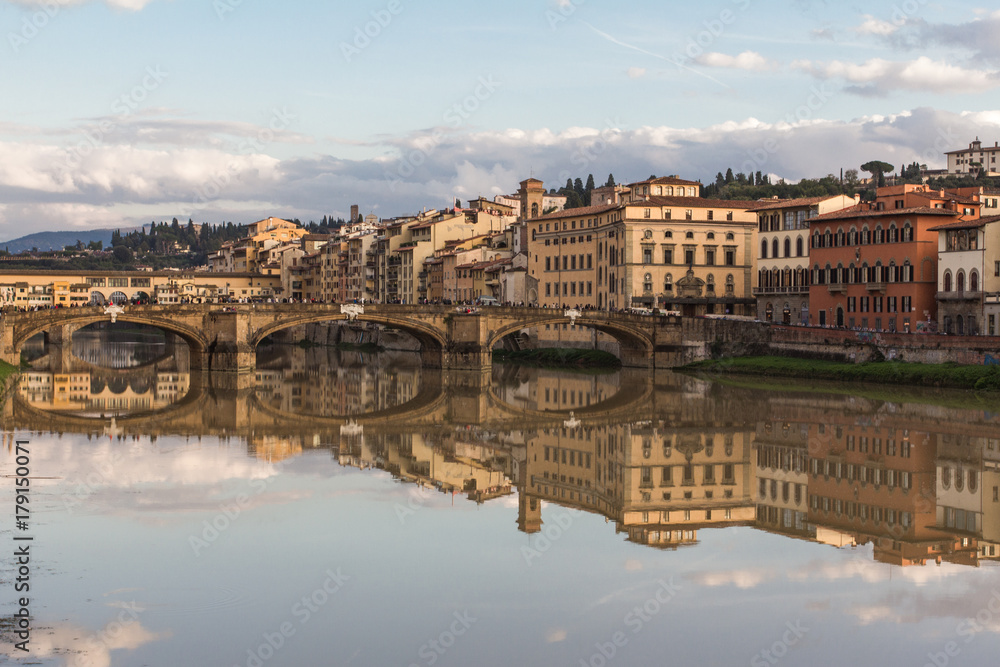 The embankment of Arno river. The bridge across the river, Florence, Italy. Reflection in the water.