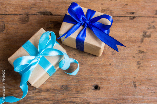 Christmas gift or New Year with blue ribbon on rustic wood table on night blue bokeh background. Top view of tiny handmade gift concept.