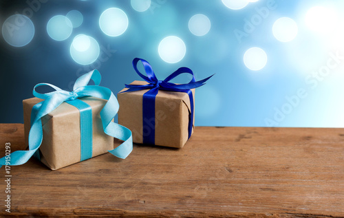 Christmas gift or New Year with blue ribbon on rustic wood table on bokeh background. Handmade gift concept.