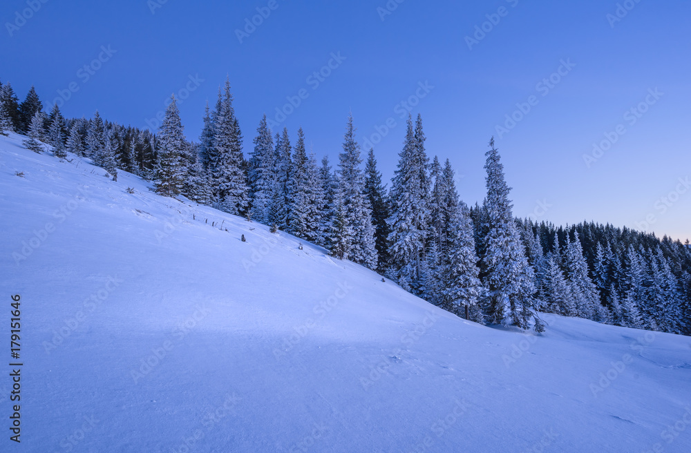 Winter landscape of a mountain slope at sunset.