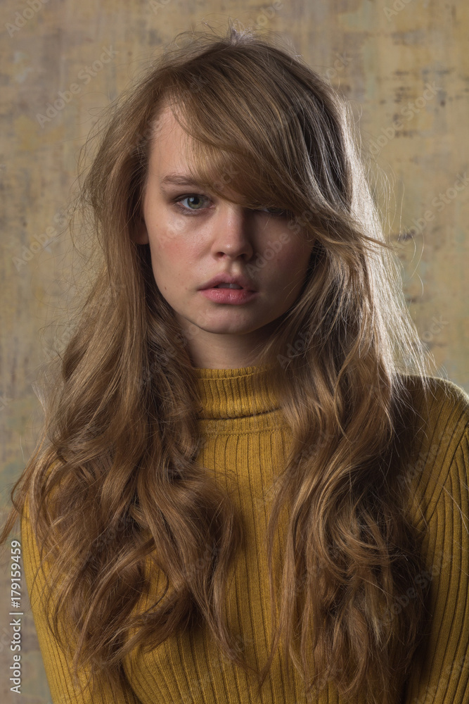 A studio portrait of a beautiful young model in warm golden and beige tones. Abstract background. A studio portrait of a beautiful young model in warm golden and beige tones. Abstract background.