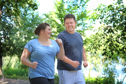 Overweight couple running in green park photo