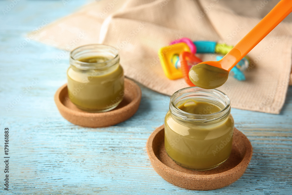 Spoon with tasty baby food over jar on table Spoon with tasty baby food over jar on table