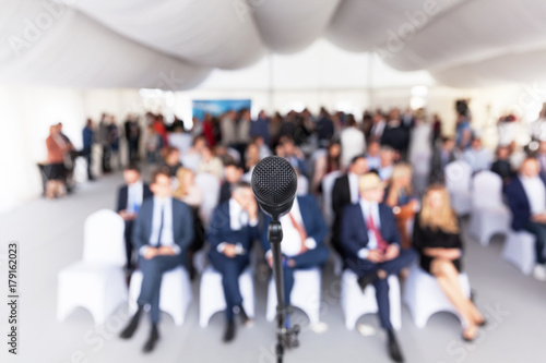Business conference. Corporate presentation. Microphone in focus against blurred audience.