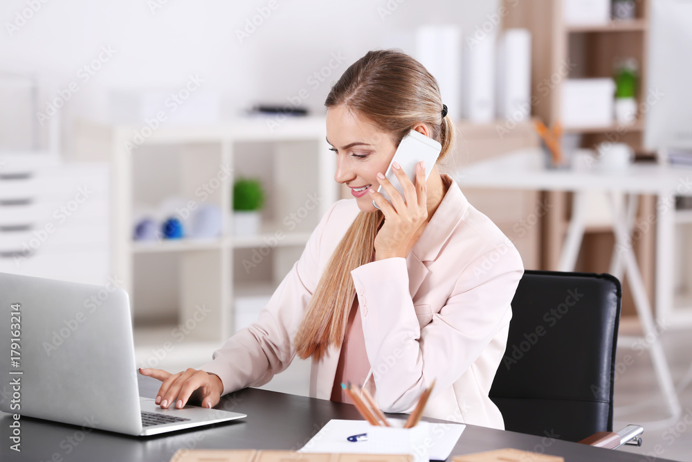 Young woman talking on phone in office Young woman talking on phone in office