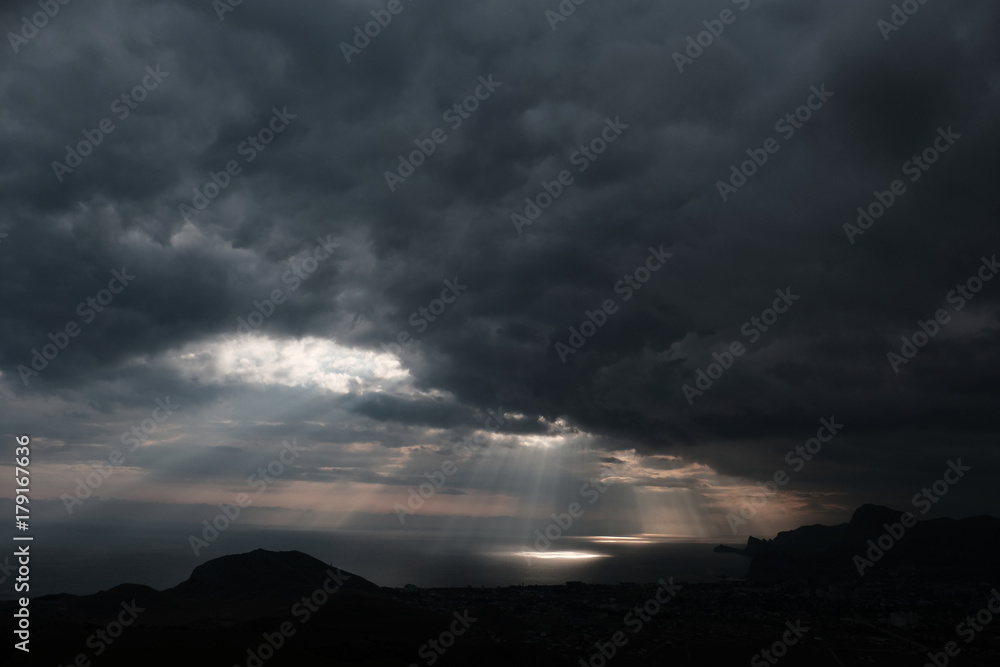 ominous clouds and the bursting rays of light over the gulf sea ominous clouds and the bursting rays of light over the gulf sea
