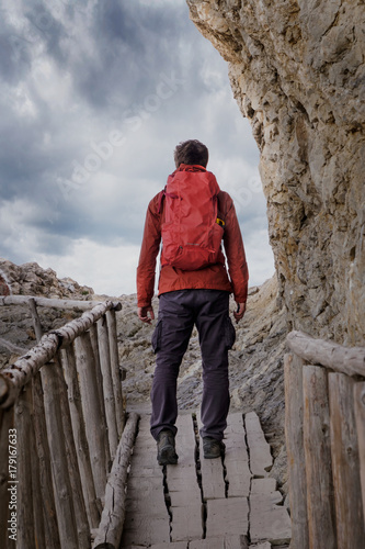 Man with a backpack during a hike on an old wooden bridge. Back to the camera © ruzvold