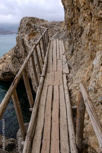 Flimsy old rotten bridge across the rocks on the sea coast