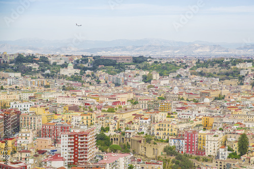 Fototapeta Naklejka Na Ścianę i Meble -  Vista panoramica della città di Napoli dal Vomero. Si può ammirare tutta la città che si estende fino al centro direzionale, dove stanno i grattacieli. Un aereo sta per atterrare.