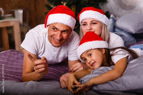 Happy family near Xmas tree. Child, mother and father having fun at home