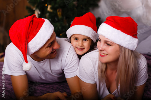Closeup portrait of cute cheerful family lying down near Christmas tree at home, happy parents with three kids celebrate New Year holiday, love concept