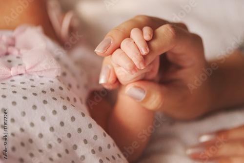 mother holds little hand of newborn baby