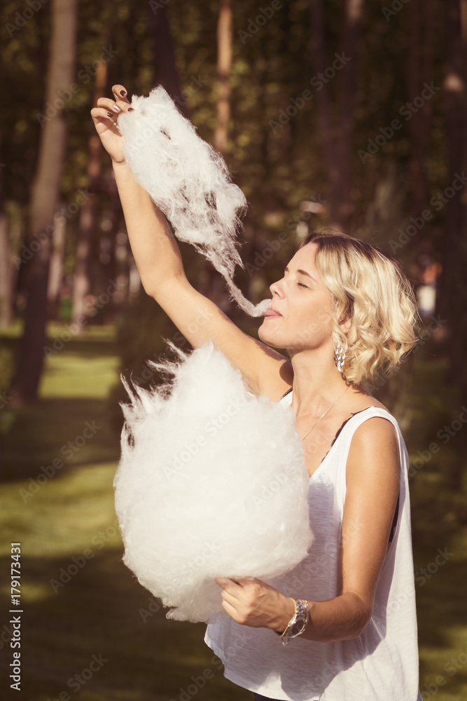 Girl eating sweet cotton candy in a summer park Girl eating sweet cotton candy in a summer park