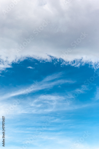Cloudy sky background. Simple cloudscape with white clouds on bright blue sky. Vertical view