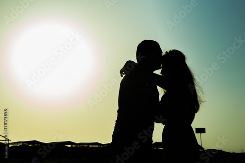 Sunset love story in the sea. Young couple make the sign of hands hearts in the air before sunrise. Silhouette at sunset. Sweethearts. Love Story. Young couple in love.