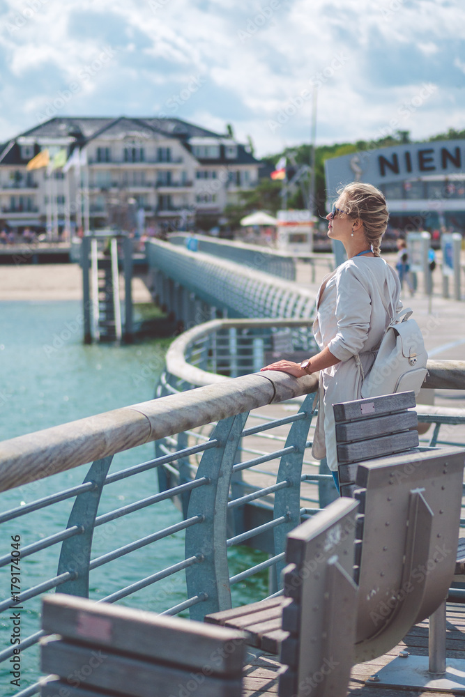 Woomen on pier near beach with roofed wicker chairs in Travemuende at the Baltic Sea. Travepromenade in Travemunde, a borough of Lubeck, Germany Woomen on pier near beach with roofed wicker chairs in Travemuende at the Baltic Sea. Travepromenade in Travemunde, a borough of Lubeck, Germany